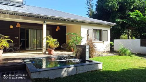 a house with a koi pond in the yard at Villa Les Jardins de la Trinité in Saint-Philippe