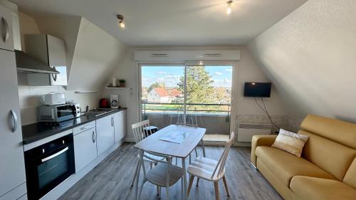 Il comprend une petite cuisine et un salon avec une table et un canapé. dans l'établissement Le calypso de la Baie, au Crotoy