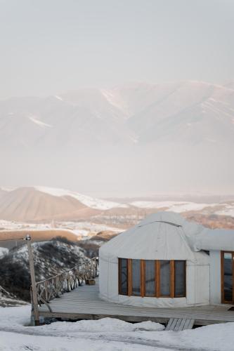 a white building in the snow with mountains in the background at Ethno complex Ala kuch in Kaindy