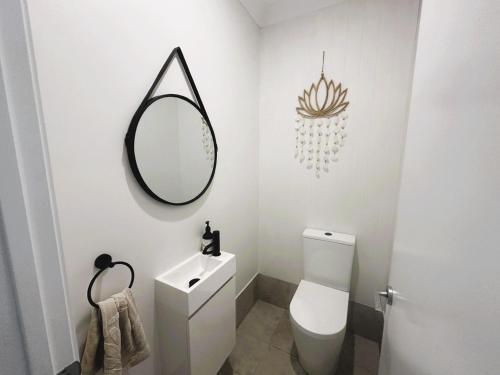 a bathroom with a white toilet and a mirror at The Mermaid's Retreat - Pool in Kiama! in Kiama