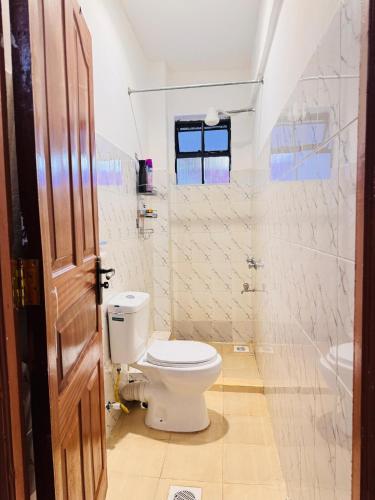 a white bathroom with a toilet and a sink at Cozy Homes in Nairobi