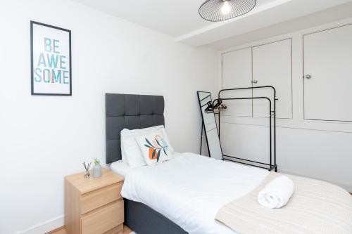 a white bedroom with a bed and a night stand at Cozy 2 Bed Apartment in City Centre-Free Parking in Southampton