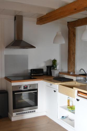 a kitchen with white cabinets and a stove top oven at Vakantieboerderij Ferme Le Bleuet in Ohey