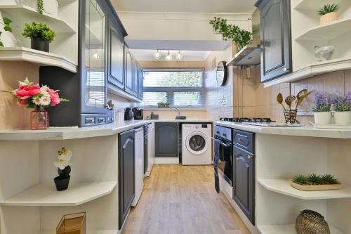 a kitchen with blue cabinets and a washer and dryer at Spacious & Modern Triple-Story Cardiff Home with Pool Table in Cardiff