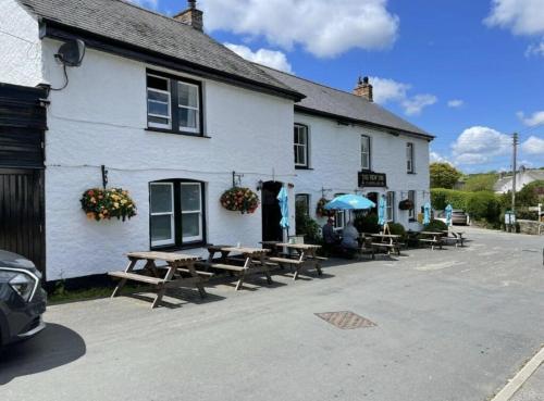a white building with picnic tables in front of it at The New Inn in Veryan