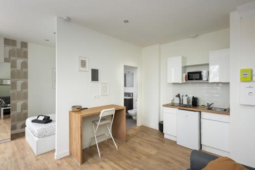 - une cuisine avec des placards blancs et un bureau dans la chambre dans l'établissement Le Terrible, à Brest