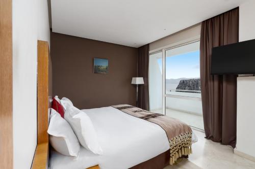 a bedroom with a white bed and a large window at Mercure Quemado Al-Hoceima Resort in Al Hoceïma