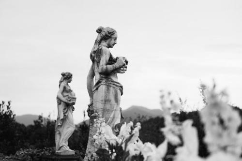 a statue of a woman standing next to flowers at Villa Lucini 1886 Garden Apt near Lake Como and Milan in Rovagnate