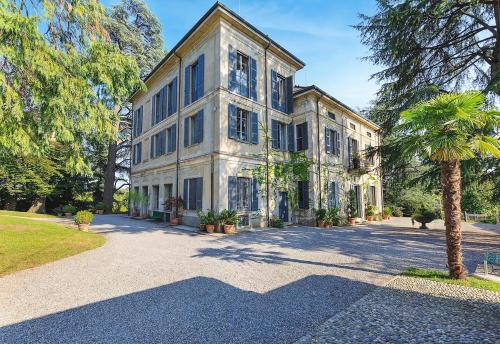 a large house with a palm tree in front of it at Villa Lucini 1886 Garden Apt near Lake Como and Milan in Rovagnate