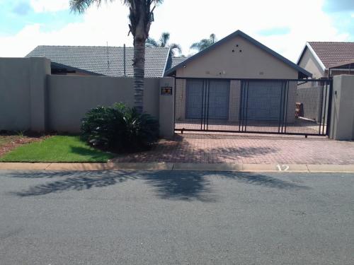 a house with a fence and a palm tree at Falconbridge Properties in Krugersdorp