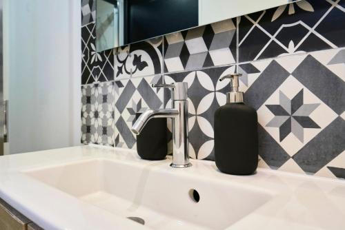 a bathroom sink with two soap dispensers on it at Maison trois chambres avec cour, parking gratuit in Croix