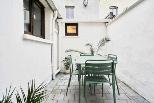 a green table and chairs on a patio at Maison trois chambres avec cour, parking gratuit in Croix
