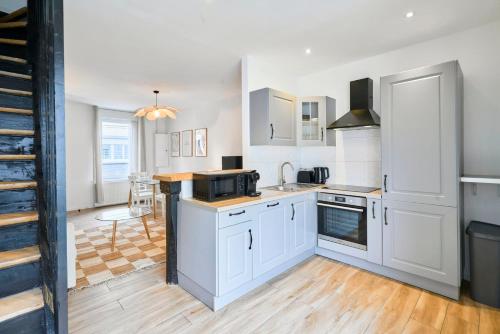 a kitchen with white cabinets and a stove top oven at Maison trois chambres avec cour, parking gratuit in Croix