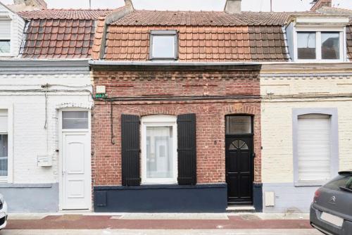 a brick building with white doors and a red roof at Maison trois chambres avec cour, parking gratuit in Croix