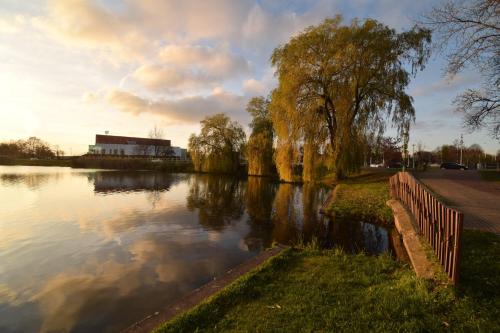 a river with a fence and trees and a building at Suwałki Centrum Studio in Suwałki