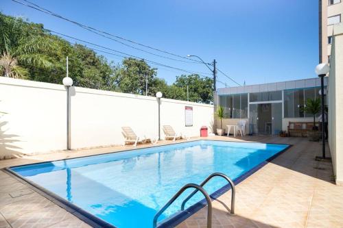 a large swimming pool with chairs and a building at Apartamento encantador San Roman in Bauru