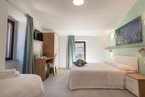 a hotel room with two beds and a desk at Le Dimore della Custodia in Assisi