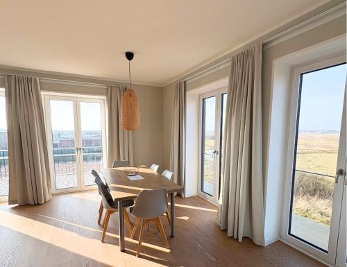 a dining room with a table and chairs and windows at Westeroog in Wangerooge