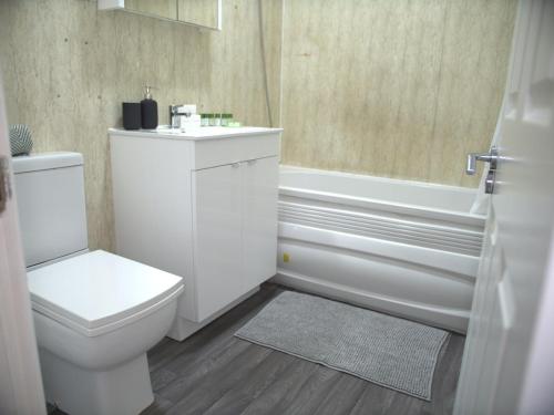 a bathroom with a toilet and a tub and a sink at Stylish 4 Bd Ft LDN Parking in London