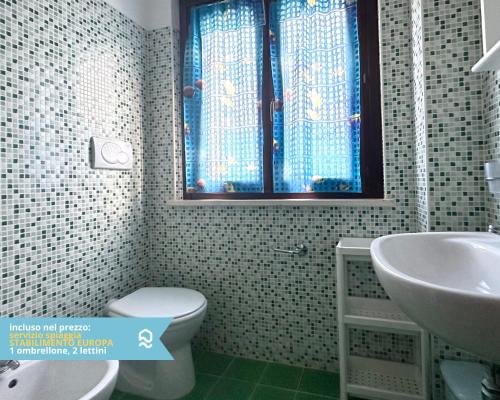 a bathroom with a toilet and a sink and a window at RS314 - Marcelli, bilocale in residence fronte mare in Marcelli