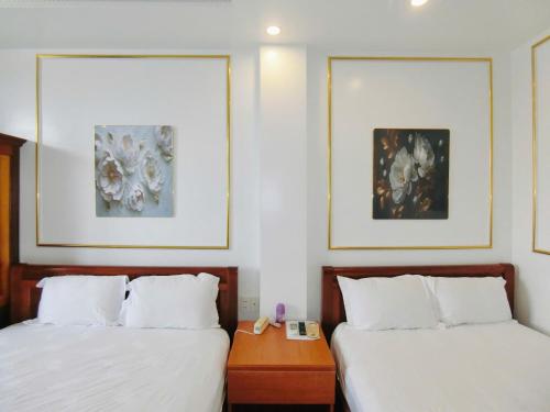 two beds in a hotel room with paintings on the wall at Ngọc Châu Hotel in Vung Tau