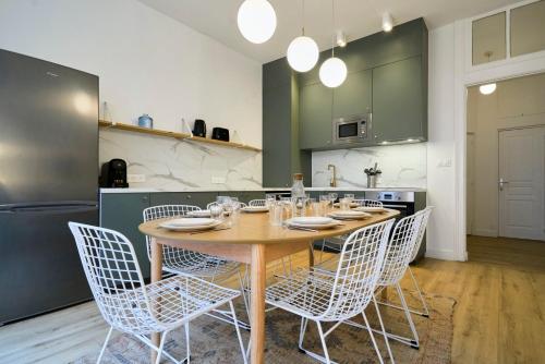 eine Küche mit einem Holztisch und weißen Stühlen in der Unterkunft Maison 5 chambres & 5 sdb proche métro & commerces in Lille