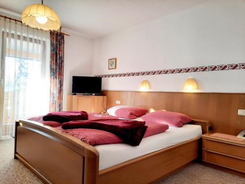 a bedroom with a large bed with red pillows at Pension Schwaiger in Bad Gögging