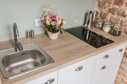 a kitchen counter with a sink and a vase of flowers at Simply Modern Apartments in Toruń