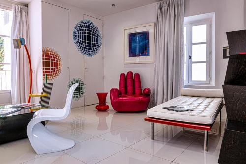 a living room with a red chair and a couch at Palais Aoma, hôtel particulier de luxe en Provence in LʼIsle-sur-la-Sorgue
