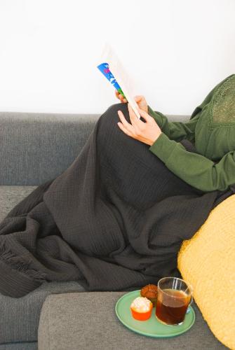 une femme qui se couche sur un canapé en lisant un livre avec une assiette de nourriture dans l'établissement Fanfrelin joli T3 centre ville, à Angoulême