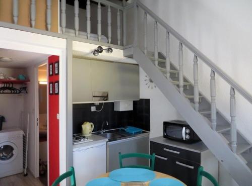 une petite cuisine avec un escalier dans une petite maison dans l'établissement Appartement saisonnier à la semaine, au Cap d'Agde