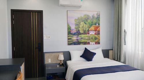 a bedroom with a bed and a painting on the wall at Royal Homestay And Coffee in Thôn Lại Thê
