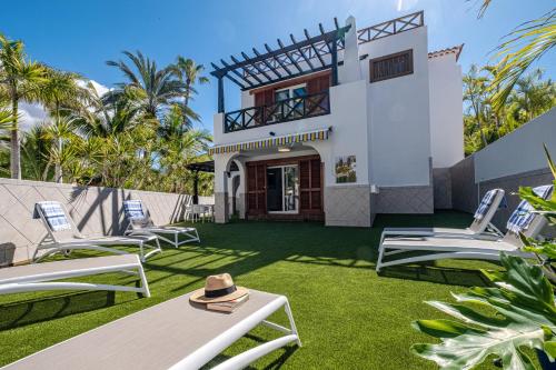 a villa with a lawn with lounge chairs at Parque Santiago III Official in Playa de las Americas