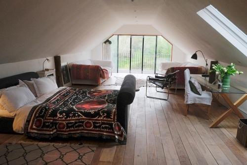 a bedroom with a bed and a couch in a attic at The Long Barn at Brandiers in Minety