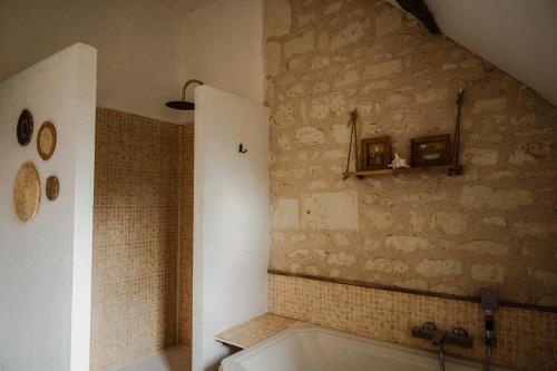 a bathroom with a stone wall and a bath tub at Vakantiewoning BienViennue in Marcilly-sur-Vienne