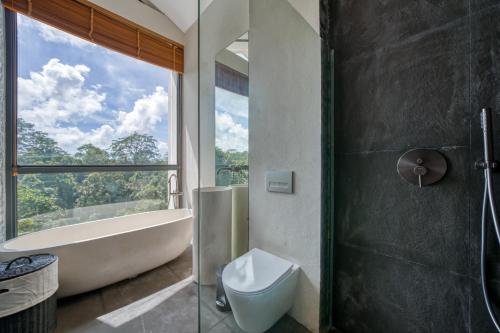 a bathroom with a tub and a toilet and a sink at Loyo Villas in Tegalalang