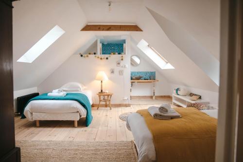 a attic bedroom with two beds and a staircase at Magnifique maison pour 8 avec jardin in Guissény