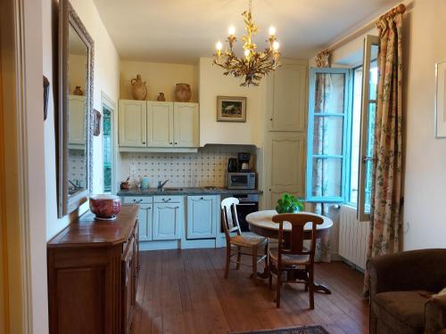 une cuisine avec des armoires bleues et une table et des chaises dans l'établissement La Treille, maison de charme au coeur de Beynac, à Beynac-et-Cazenac