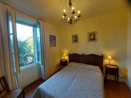une chambre avec un lit, une fenêtre et un lustre dans l'établissement La Treille, maison de charme au coeur de Beynac, à Beynac-et-Cazenac