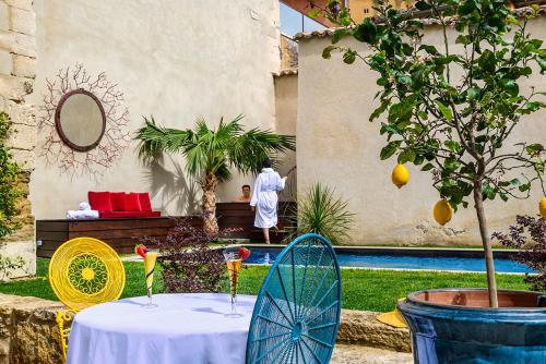 a table with two chairs and a man standing in a yard at Palais Aoma, hôtel particulier de luxe en Provence in LʼIsle-sur-la-Sorgue