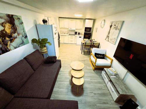 salon z kanapą i kuchnią w obiekcie Appartement T2 confortable - Piscine et Jacuzzi w mieście Pierrelaye