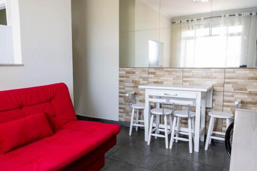 Una sala de estar con un sofá rojo y una mesa. en Otimo apartamento a 200m do mar com WiFi, en Campo Grande
