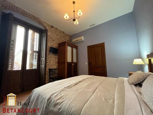 a bedroom with a large bed and a chandelier at Hotel Casa Rural Betancourt in Almadén