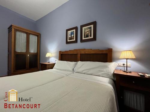 a bedroom with a large white bed with two lamps at Hotel Casa Rural Betancourt in Almadén