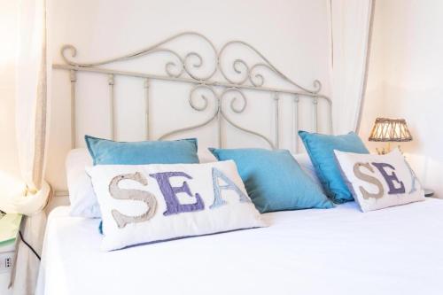 a white bed with blue pillows with the words sesi at Bòmera Rooms in Gallipoli
