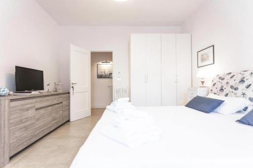 a white bedroom with a large bed and a flat screen tv at Bòmera Rooms in Gallipoli