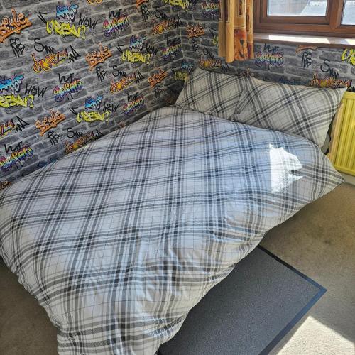 a bed with a checkered pillow with a tiger on it at Peace and Love House in Kent