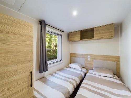 deux lits dans une chambre avec une fenêtre dans l'établissement Mobile home in the Bay of Bonne Anse Plage La Palmyre, aux Mathes