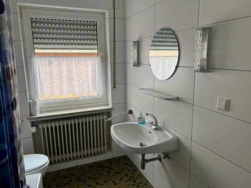 a bathroom with a sink and a toilet and a window at Ferienwohnung mit 4 Betten - Balkon - Küche in Fuldabrück