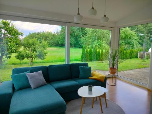 a living room with a blue couch and a large window at Ferienwohnung "Auszeit im Grünen" in Bad Schussenried